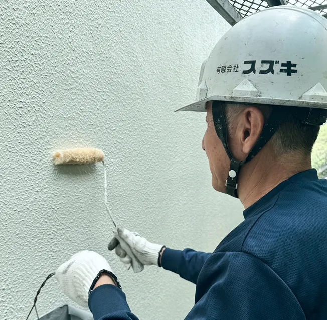 落ち着いた色合いの壁に、ローラーで均一に塗料を塗る作業風景。